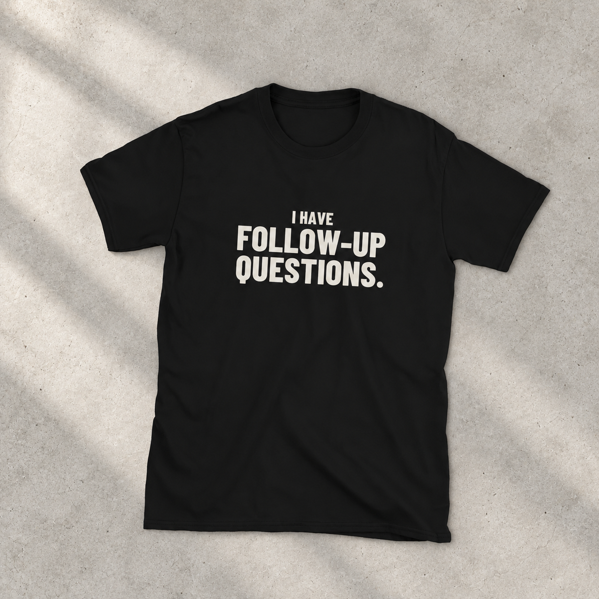 Black Follow-Up Questions statement T-shirt, full front view on a light warm-gray studio surface, with offwhite I HAVE / FOLLOW-UP / QUESTIONS. print. Custom product mockup.
